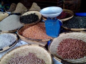 Baskets of assorted dried beans and a weighing scale at a market stall