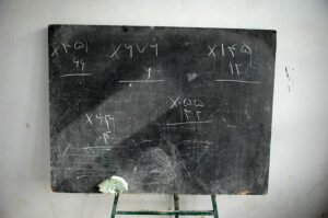 A chalkboard with math problems at the front of a classroom
