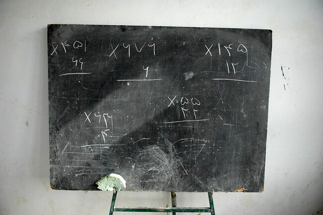 A chalkboard with math problems at the front of a classroom